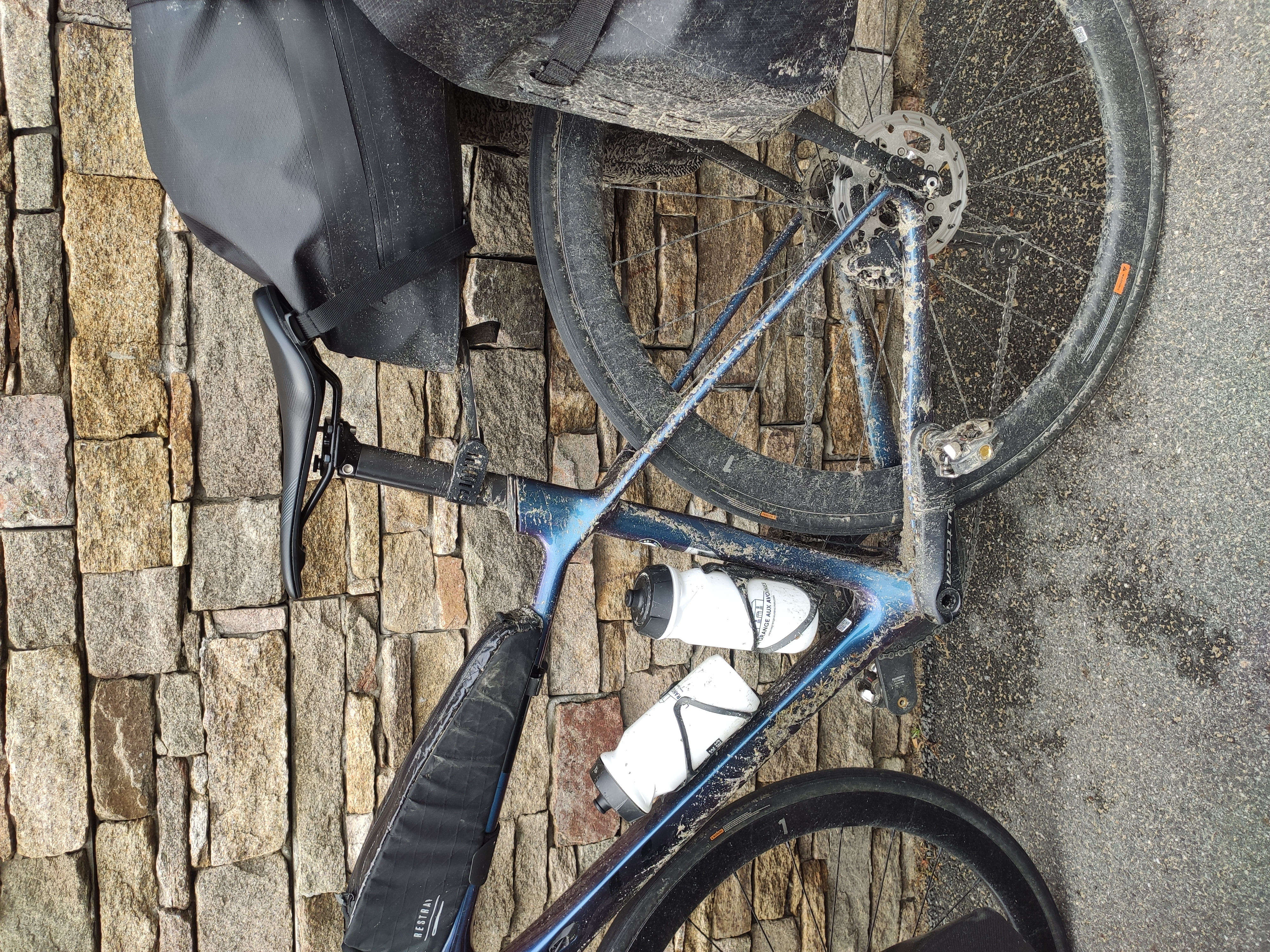 Vélo de bikepacking chargé de sacoches, couvert de poussière, appuyé contre un mur de pierre